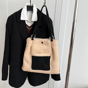 Close-up of oatmeal faux shearling tote bag with black leather pocket and silver hardware
