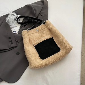Detail view of beige faux shearling bucket bag with black contrast pocket and strap