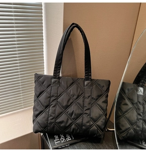 Detail of classic diamond quilted embroidery on large black nylon tote bag with reinforced strap