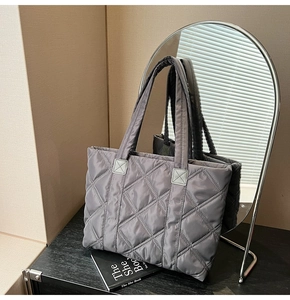 Detail of grey quilted nylon tote bag with elegant diamond embroidery and shoulder strap