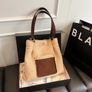 Detail of beige faux shearling tote bag with brown leather pocket in luxury gift box