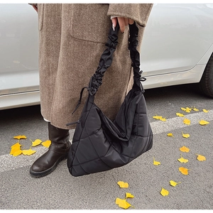 Close-up of black quilted nylon dumpling bag with ruffled shoulder strap and drawstring