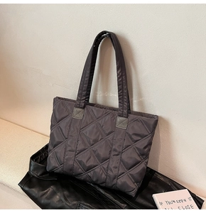 Detail of dark grey quilted nylon tote bag showing diamond embroidery and light texture