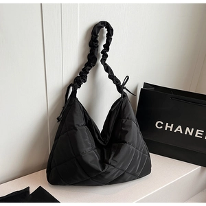 Detail of black quilted hobo bag with large diamond stitching and ruched shoulder strap