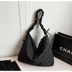 Close-up of quilted nylon tote bag with glossy finish and ruched puff shoulder strap