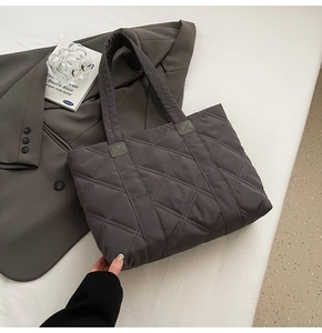 Detail of grey quilted nylon tote bag with rhombus embroidery on stylish grey suit blazer