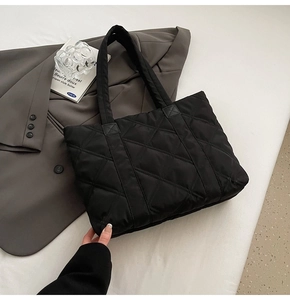 Detail of black quilted nylon tote bag featuring oversized diamond stitching and soft texture