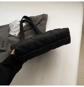 Detail of the black quilted tote bag base showing spacious structure and diamond stitching