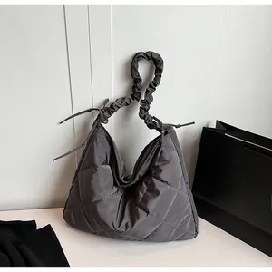 Macro detail of dark grey quilted nylon hobo bag with scrunchie strap and drawstring ties