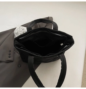 Detail view of large black quilted nylon tote bag showing spacious interior with zipper pocket