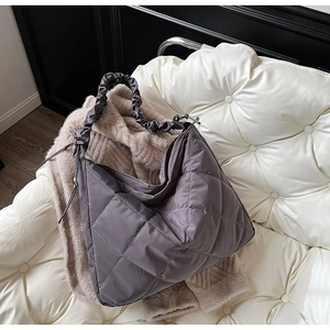 Detail of grey quilted nylon tote bag featuring diamond patterns and ruched strap design