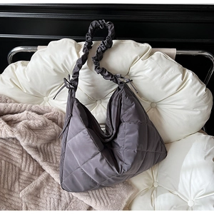 Close-up of quilted grey tote bag showing diamond stitching and ruched shoulder strap