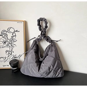 Detail of dark grey quilted nylon tote bag with ruched handles and a bow accent