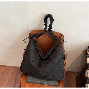 Detail of black quilted nylon tote bag with scrunchie strap on vintage wooden chair