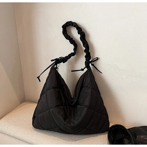 Detailed view of black quilted nylon tote featuring ruched drawstring straps and bow accents