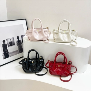 Glossy patent leather pleated handbags in pink, black, red, and white on a modern display