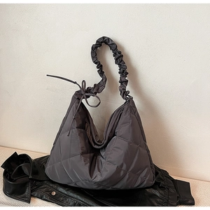 Detail of dark grey quilted nylon tote with diamond pattern and ruffled shoulder strap