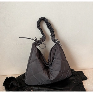 Detail of dark grey quilted tote bag featuring ruffled cloud-style shoulder strap and knot