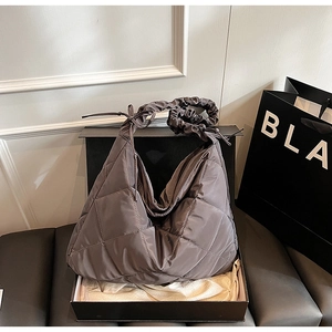 Macro detail of dark brown quilted nylon hobo bag in a stylish black gift box