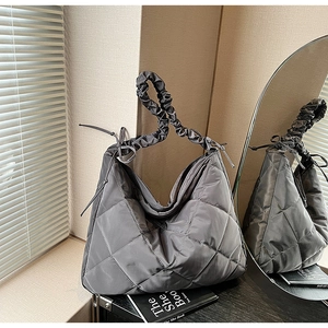 Detailed close-up of grey quilted nylon hobo bag with pleated shoulder strap and bow