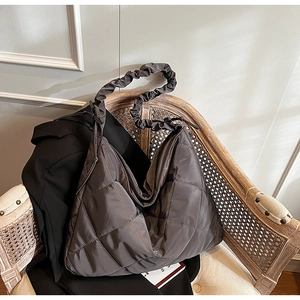 Detail of grey quilted nylon hobo bag with ruched shoulder strap on a rattan chair