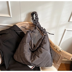 Detail of quilted dark grey nylon tote featuring a stylish ruched shoulder strap design