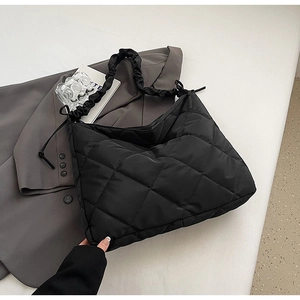 Detail of black quilted nylon tote bag with ruched handle and side drawstring ties