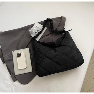Detailed view of black quilted nylon tote bag with ruched strap and spacious interior