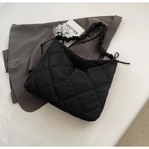 Macro detail of black quilted nylon texture and ruched strap on cloud shoulder bag