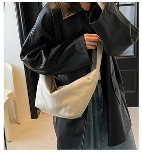 Detail of a beige knotted shoulder bag on a model with minimalist geometric stitching