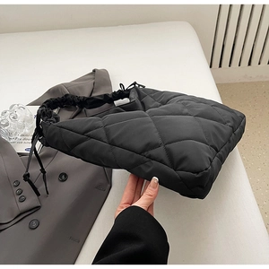 Detail view of black quilted nylon dumpling bag with pleated shoulder strap and diamond pattern