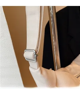 Detail of adjustable wide shoulder strap with silver buckle on beige leather bag