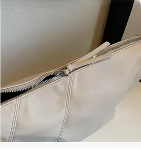 Detail of silver zipper closure and leather puller on the beige leather dumpling bag