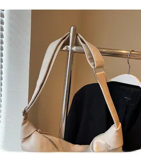 Detail view of cream leather dumpling bag featuring silver hardware and wide shoulder strap