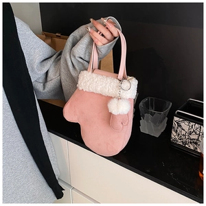 Detail of pink mitten-shaped handbag with plush trim and decorative pom-pom accessory