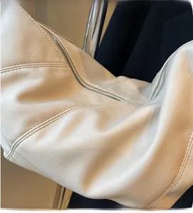 Close-up of off-white dumpling bag showing pebbled leather texture and zipper detail