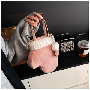 Detail of pink glove-shaped crossbody bag with white faux fur trim and pom-pom charm