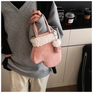 Detailed close-up of pink mitten-shaped handbag with white faux fur trim and pompom