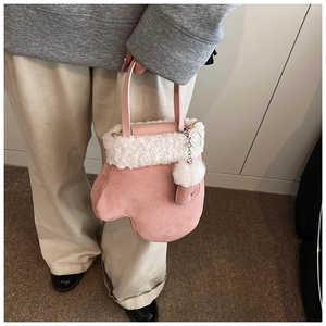 Detail of pink mitten-shaped crossbody bag with soft faux fur trim and heart charm