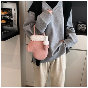 Detail of pink mitten-shaped handbag with plush trim and pompom charm in kitchen setting