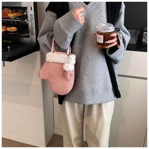 Detailed view of pink glove-shaped plush handbag with white faux fur trim and pompom