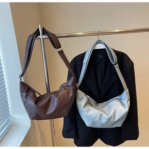 Detail of crescent hobo bags in brown and silver with adjustable wide straps and soft texture