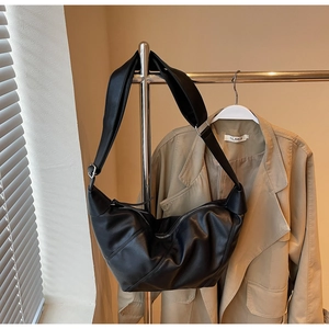 Detailed texture of black pleated leather dumpling bag with silver adjustable buckle strap