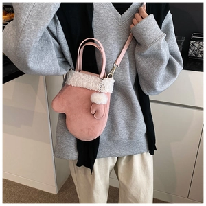 Detail of pink suede glove-shaped crossbody bag featuring white faux fur trim and mini charm
