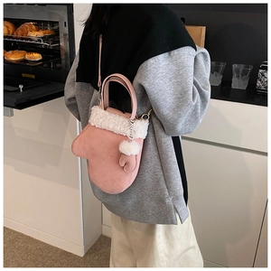 Detailed view of pink glove-shaped handbag with plush white trim and mini charm
