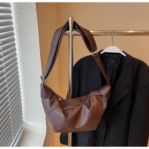 Detail view of the fine leather texture and wide shoulder strap on dark brown hobo bag