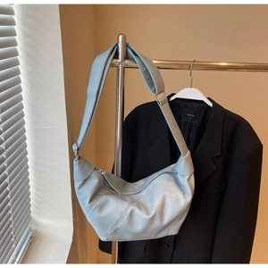 Detail of light blue crescent bag featuring diagonal stitching and wide shoulder strap