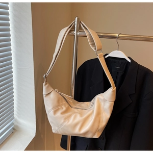 Detail of off-white crescent crossbody bag showing soft matte texture and seam stitching