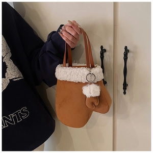 Detail of creative glove-shaped suede handbag with white faux fur trim and pom-pom charm