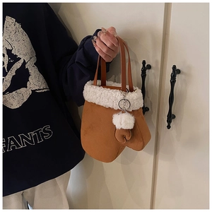 Detail of creative glove-shaped brown suede handbag with white faux fur trim and pompom